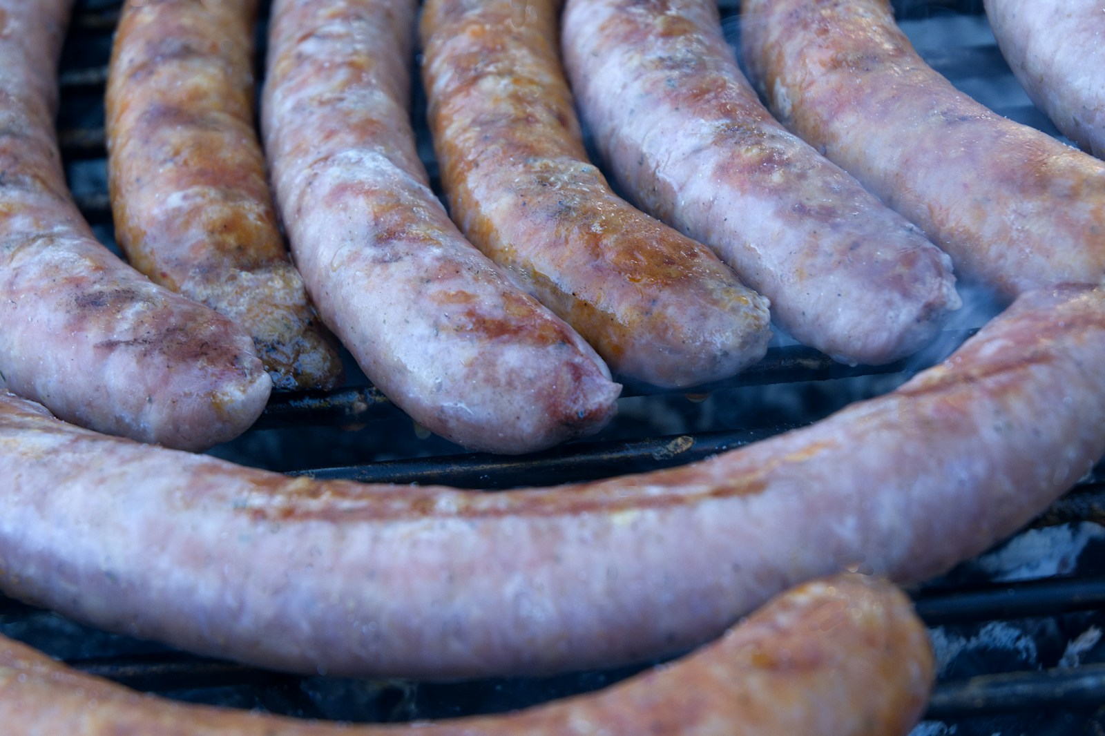 Mehrere gebräunte Bratwürste auf einem Grillrost